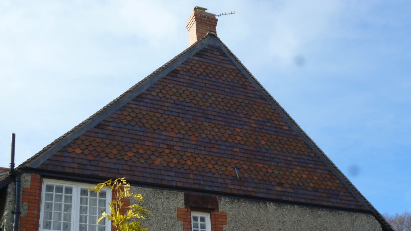 Steep gable of mottled clay plain tiles with lead-covered hips, re-roofed by M Gibson & Sons at Thornton Hough